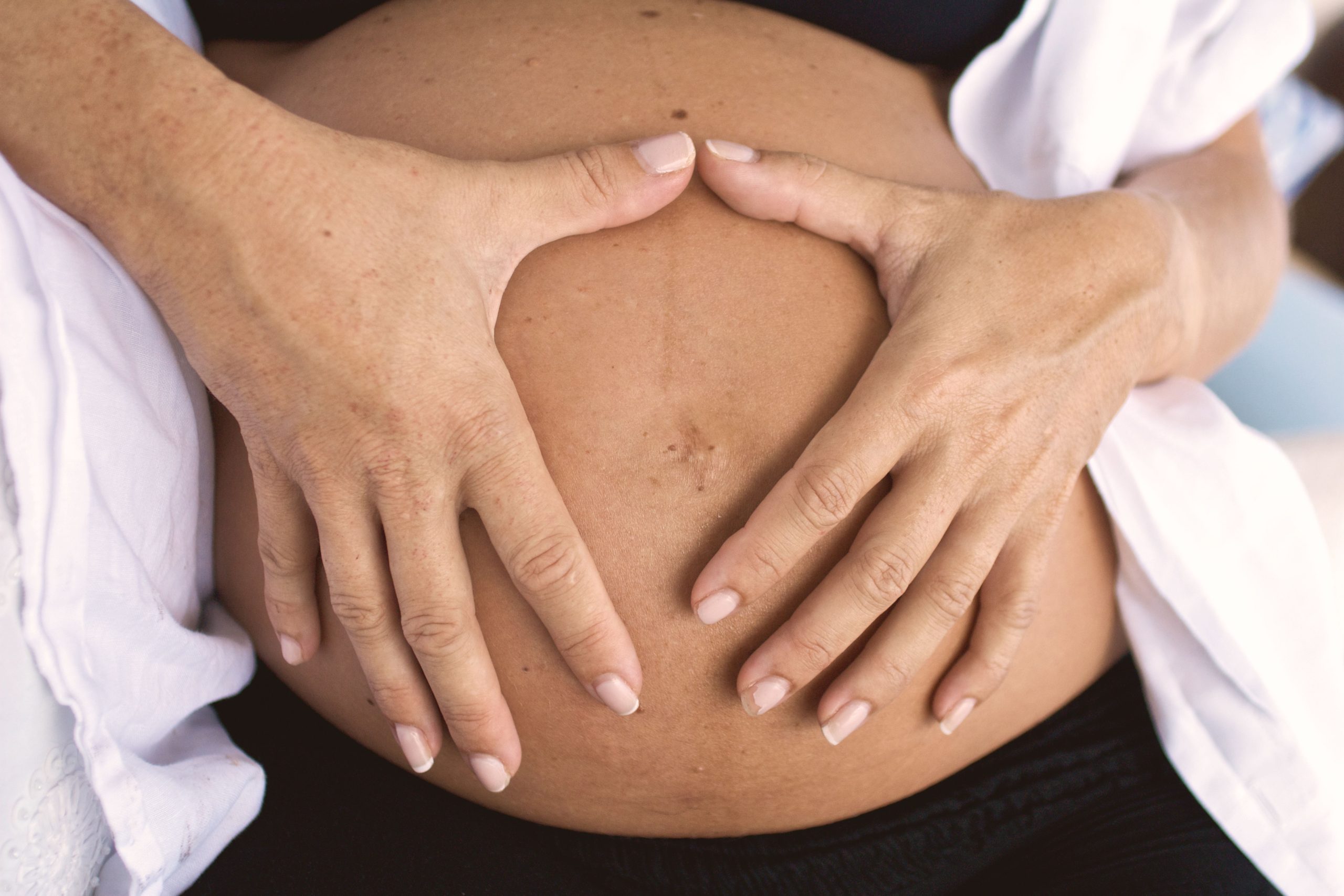 Postpartum physiotherapy client with hands forming a heart shape over her healing belly in Swords