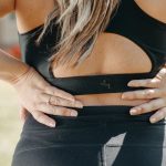 Woman holding her lower back with both hands, a common sign of low back pain or sciatica