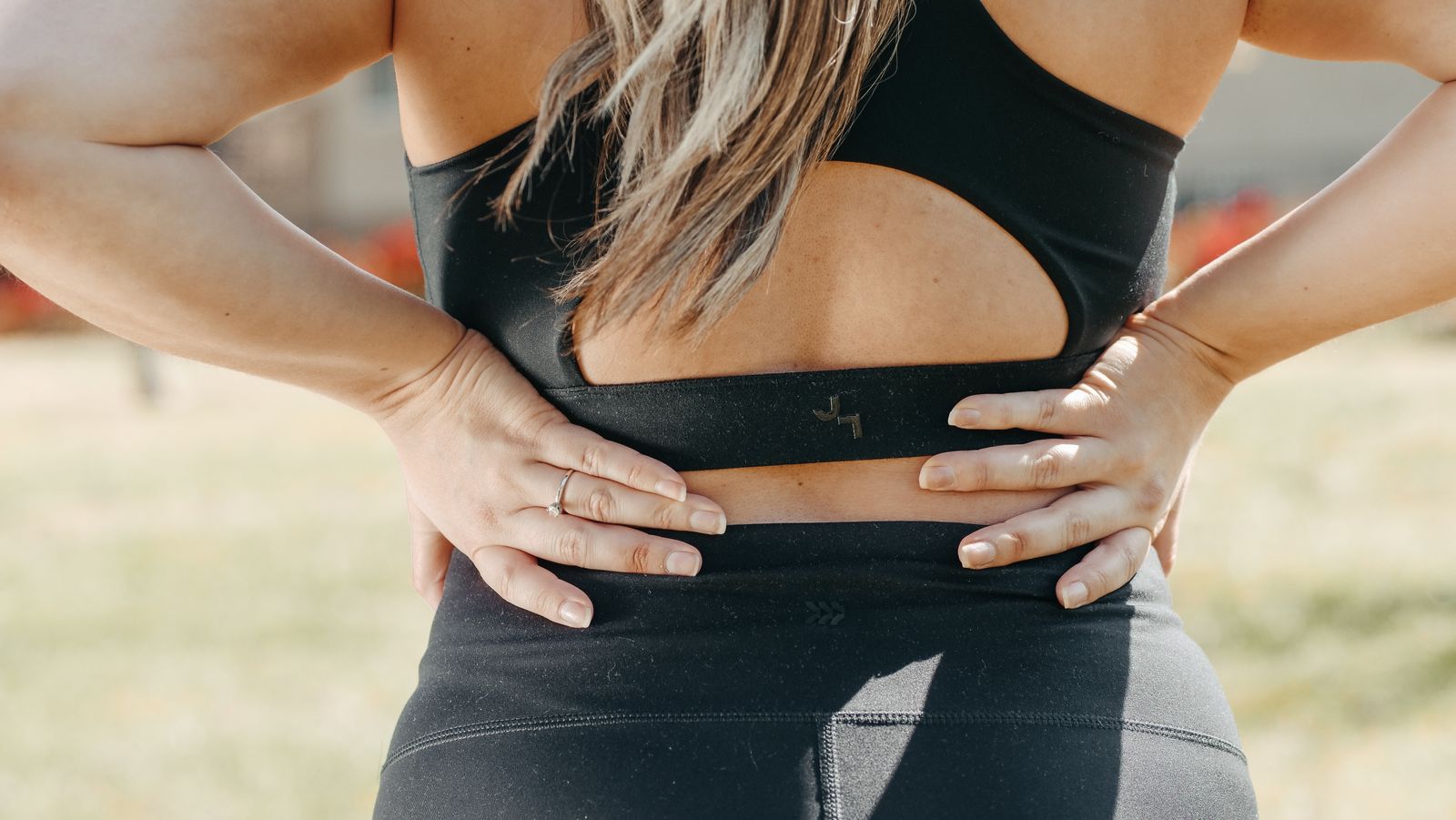 Woman holding her lower back with both hands, a common sign of low back pain or sciatica
