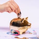 Hand placing a coin into a piggy bank on financial documents, representing tax relief savings on physiotherapy in Ireland